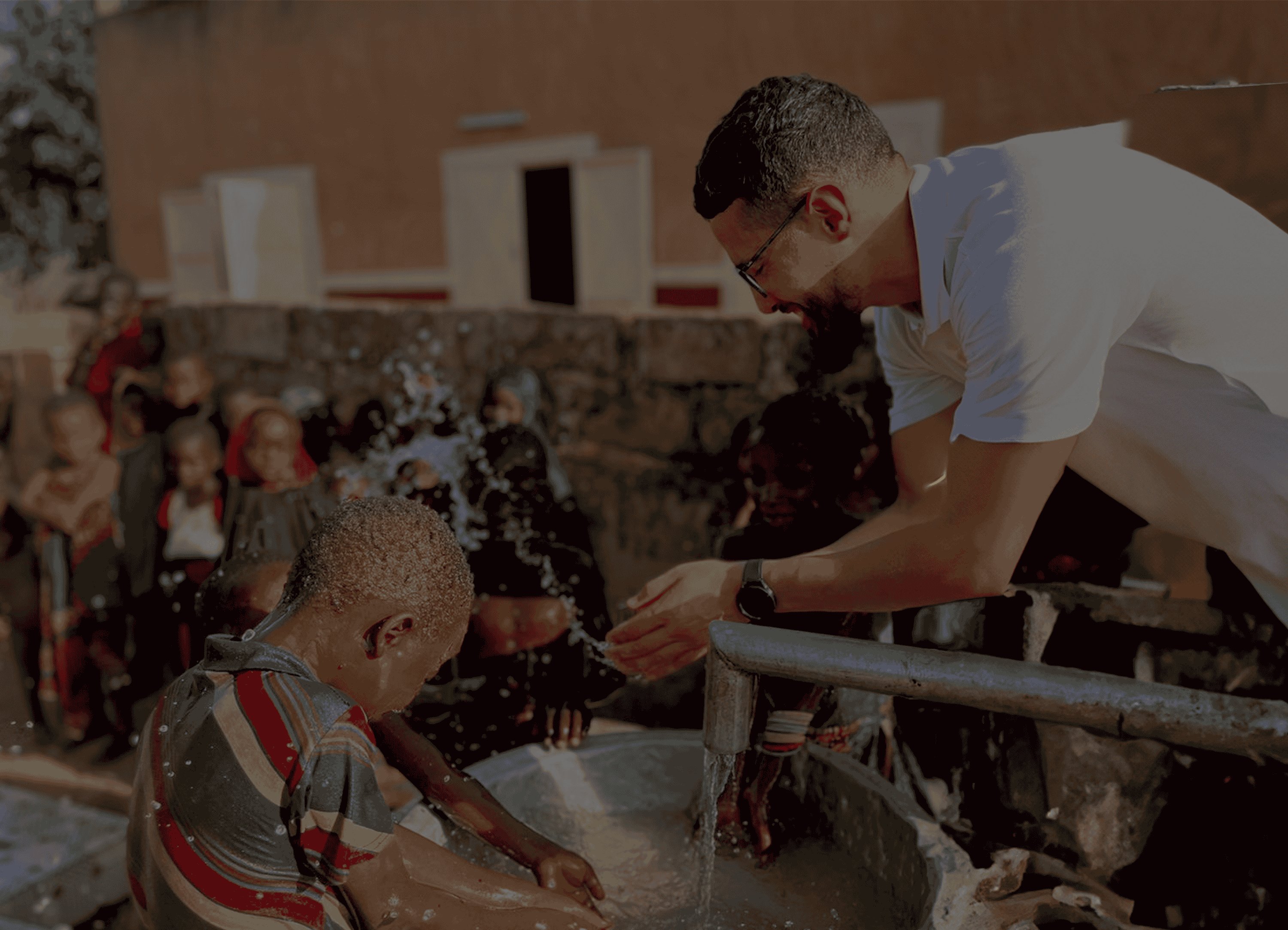 Een Bashierah-vrijwilliger geeft water aan een kind ter plaatse