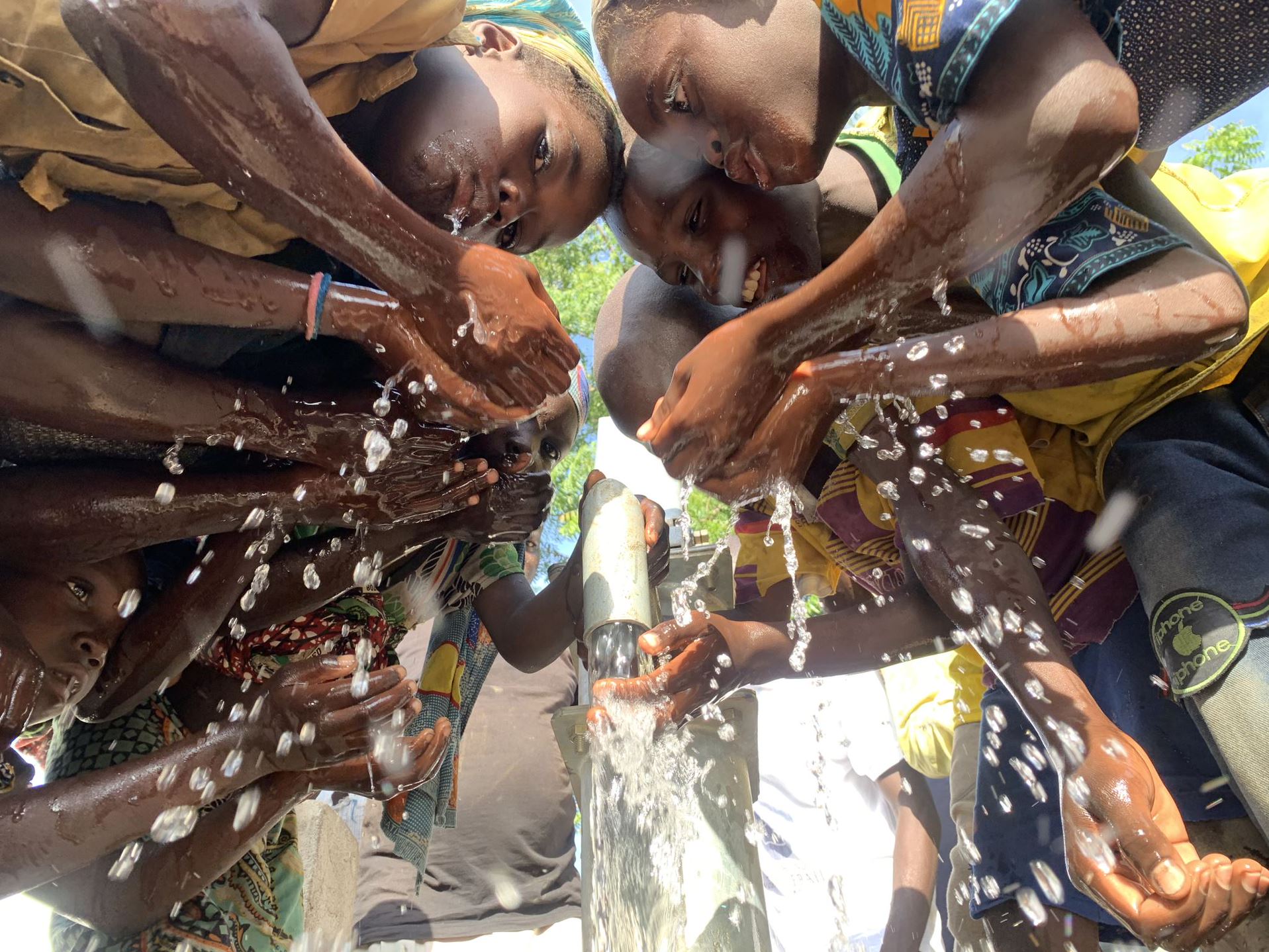 Kinderen scheppen water onder de pomp in Ghana